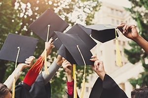 Students holding up graduation caps