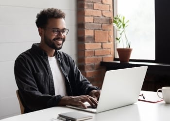 Smiling Student at Home Behind Laptop